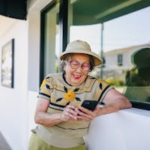 Happy senior woman texting on her phone while enjoying a sunny day outdoors.